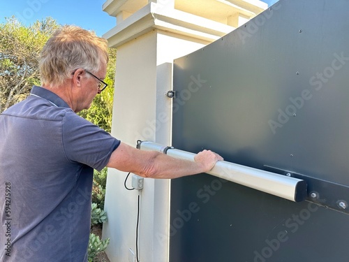 Man inspecting the hydraulic ram on an electric gate opener