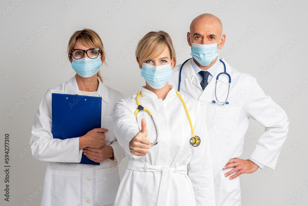 Group of medical people wearing face mask and showing thumb-up at isolated white background Group of medical people wearing face mask and showing thumb-up at isolated white background