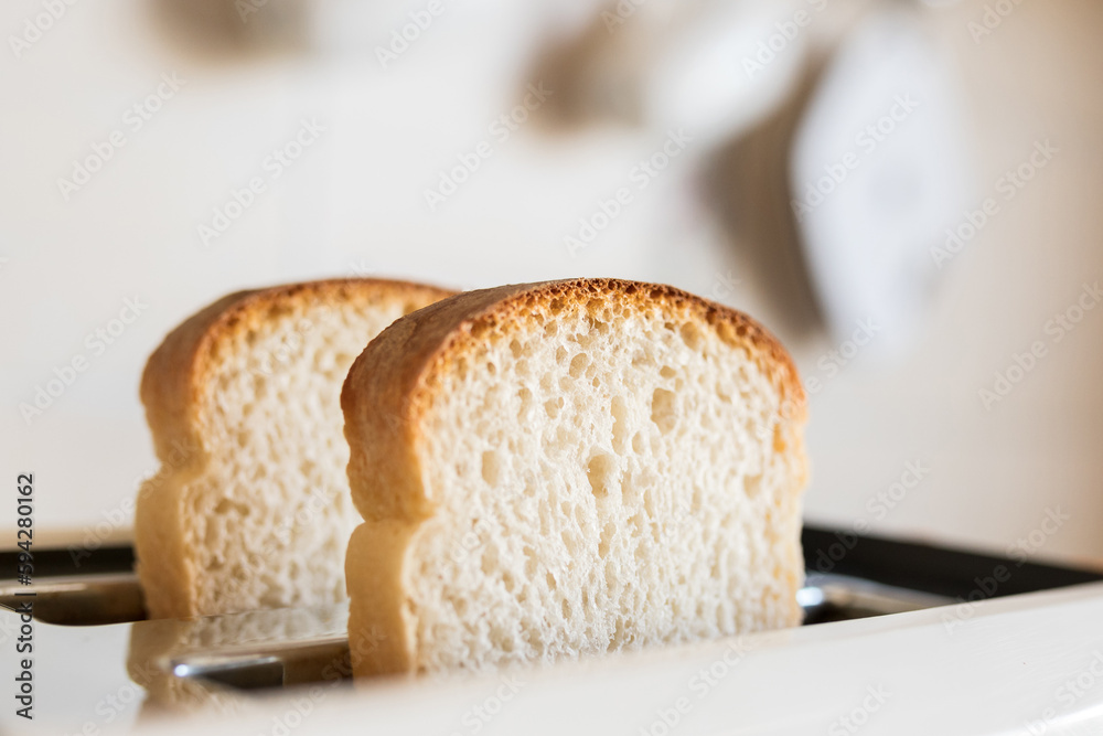 Close-up white slices of sliced bread sticking out in a white toaster, selective soft focus. Close-up white slices of sliced bread sticking out in a white toaster, selective soft focus.