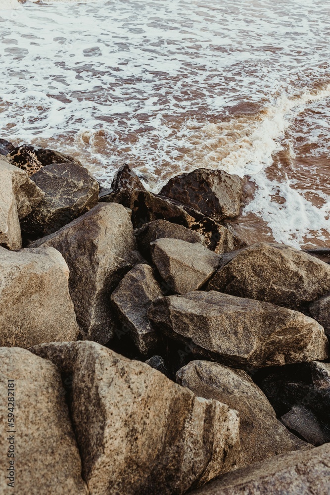 Vertical shot of waves crashing on the massive rocks on the beach, perfect for wallpapers Vertical shot of waves crashing on the massive rocks on the beach, perfect for wallpapers