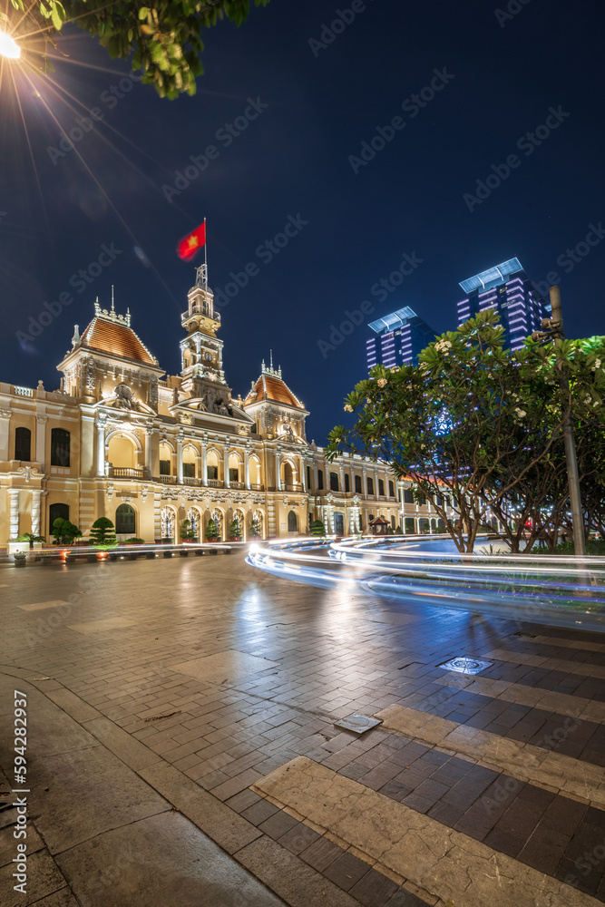 Naklejka premium Traffic in front of Ho Chi Minh City Hall, Saigon City Hall or Committee Head office in the evening, Vietnam. Light trail and night. Popular place to visit in Saigon. Travel destinations in Vietnam