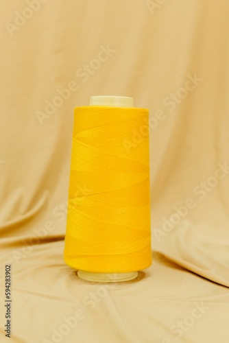 Vertical close-up photograph of a yellow spool of thread
