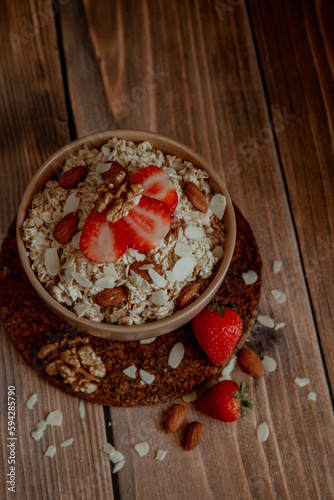 Oatmeal porridge with strawberries and nuts on dark wooden background