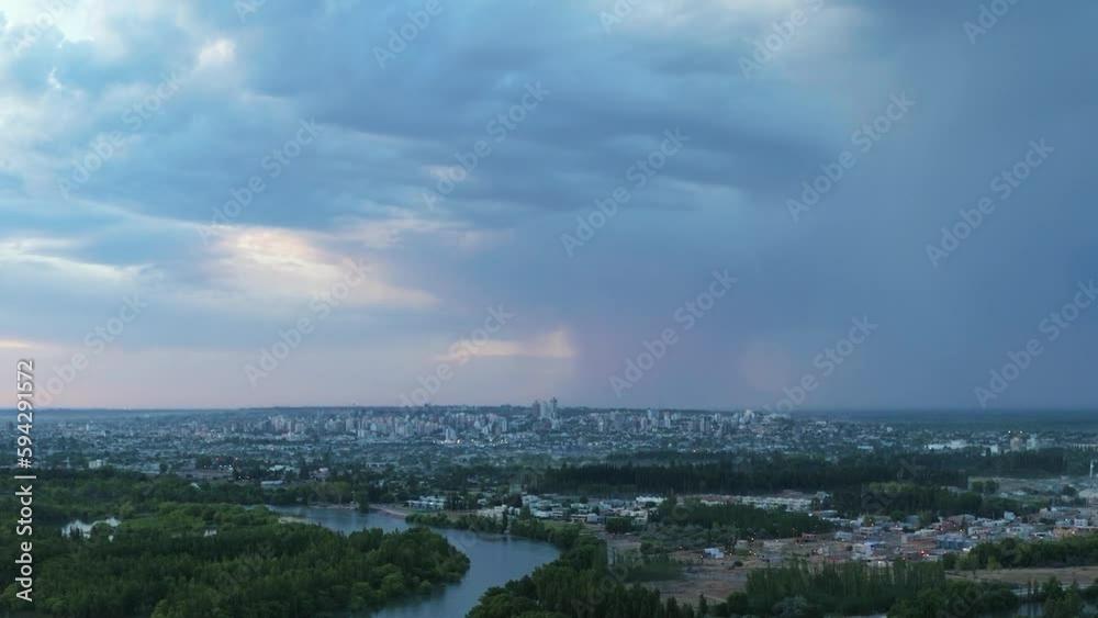 Stormy sunset by rivers with the background you can see the city of Neuquen Capital under a summer thunderstorm. Patagonia, Argentina Stormy sunset by rivers with the background you can see the city of Neuquen Capital under a summer thunderstorm. Patagonia, Argentina