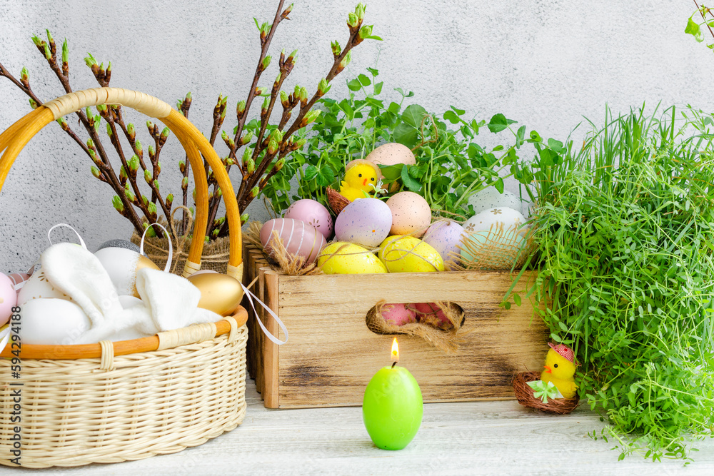 Easter colorful eggs and yellow decorative chickens among greenery in a box and basket decorated with greenery. Easter celebration