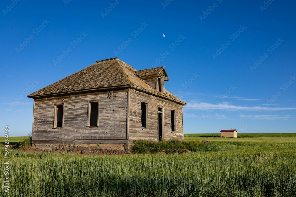Derelict, abandoned house in an open grassland area on a sunny day Derelict, abandoned house in an open grassland area on a sunny day