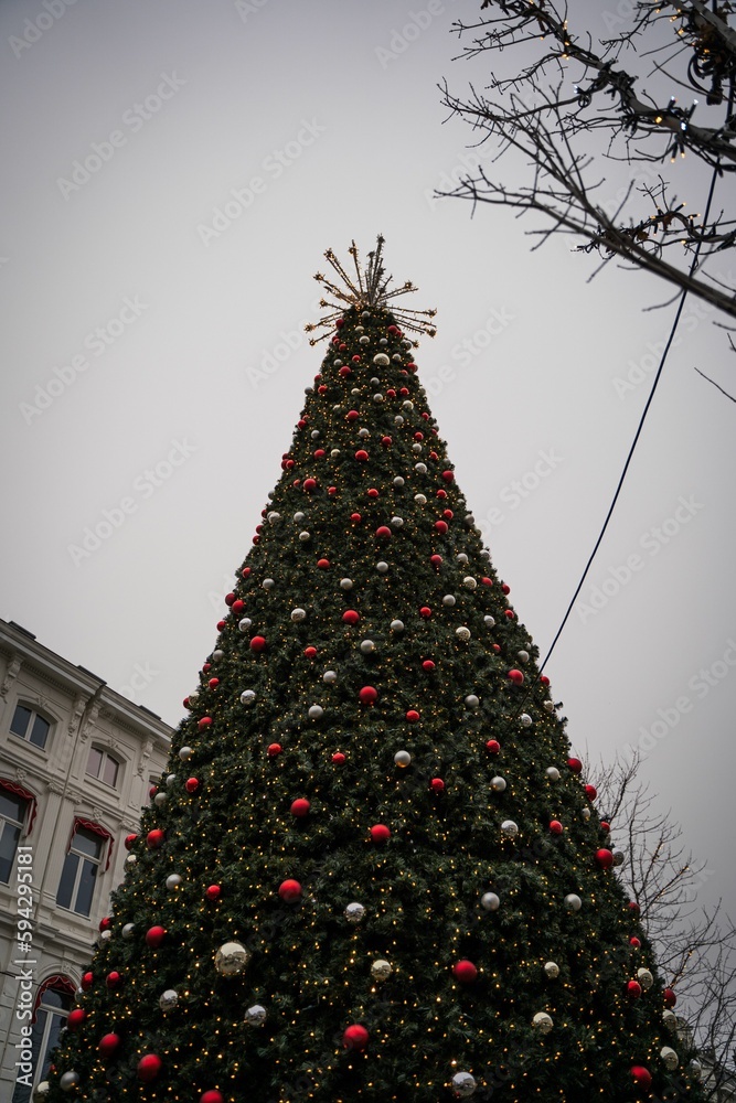 Fototapeta premium Vertical low angle shot of a Christmas tree decorated with Christmas baubles