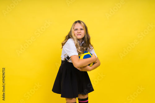 Portrait of a cute eight year old girl in volleyball outfit isolated on red yellow background © Ivan Zelenin