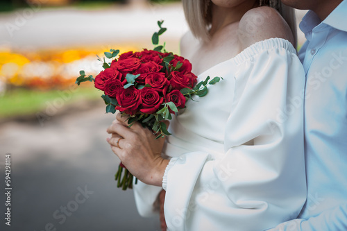 Fototapeta Naklejka Na Ścianę i Meble -  Bouquet of red roses in the hands of the bride. Bridal bouquet in woman's hands