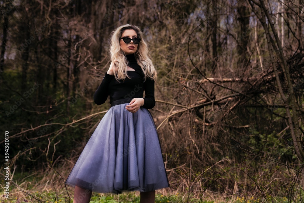 Beautiful young female in a black top and a purple skirt posing in a park Beautiful young female in a black top and a purple skirt posing in a park