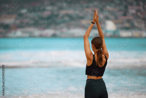 Make the time to take care of your soul. Rearview shot of a young woman meditating while practising yoga at the beach.