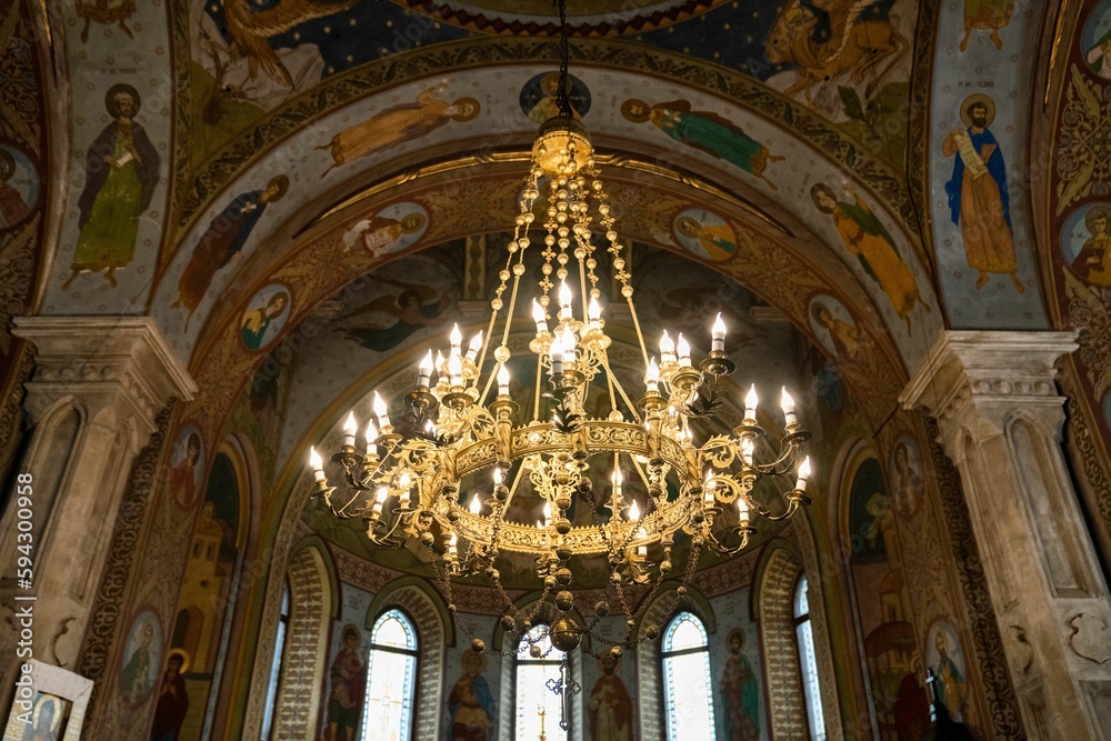 Chandelier in an Orthodox church hanging from the ceiling with pictures of saints.