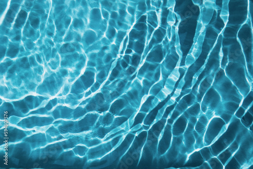 Abstract nature textured background, water waves in the pool with sun reflection, clear blue water