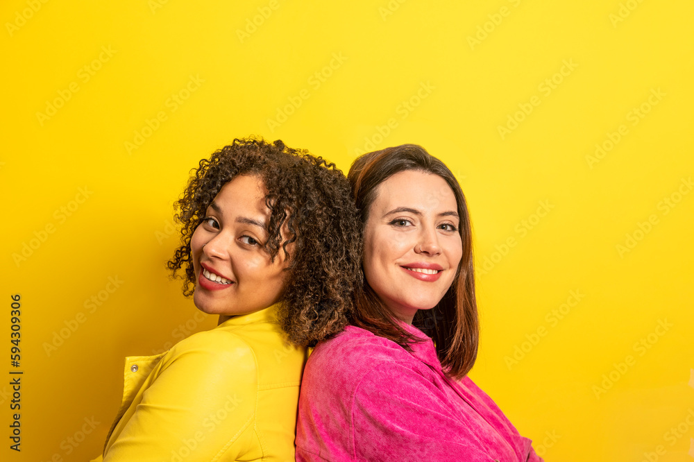 Cheerful multiethnic friends looking at camera against yellow background Cheerful multiethnic friends looking at camera against yellow background