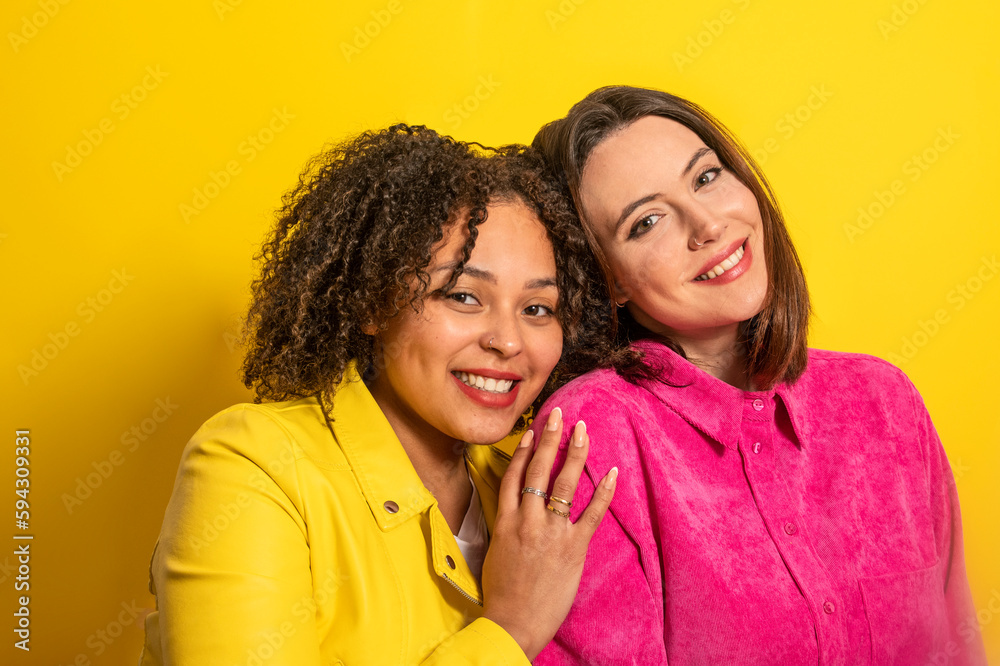 Cheerful multiethnic friends looking at camera against yellow background Cheerful multiethnic friends looking at camera against yellow background