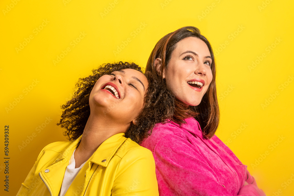 Cheerful multiethnic friends looking away against yellow background Cheerful multiethnic friends looking away against yellow background