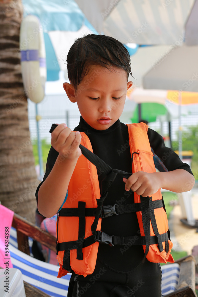 Asian boy wearing life jacket before playing in pool. Kid with life