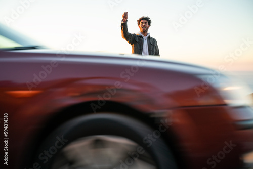 Black man with skateboard hitchhiking on road