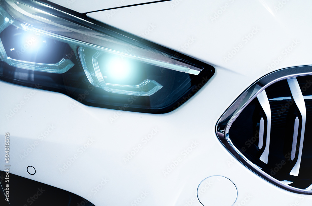 Closeup headlamp light of a white luxury car. Automotive industry concept. Electric car or hybrid vehicle concept. Automobile leasing and insurance concept. Auto leasing business. Electric vehicle.