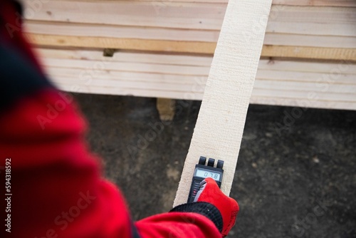 Closeup of a man checking the wooden planks with a moisture meter.