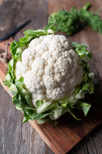 Whole cauliflower with leaves isolated on wooden table with copy space