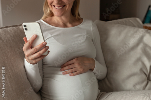 Pregnant woman holding her belly and her phone