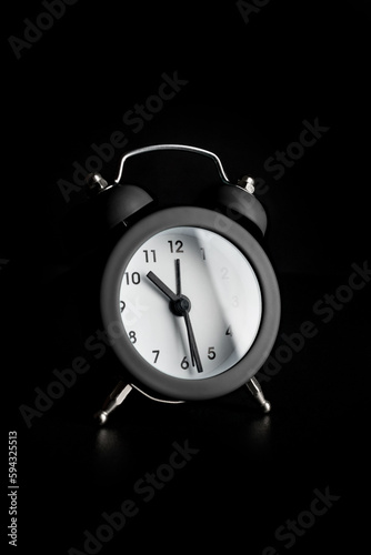Small alarm clock on a black background.