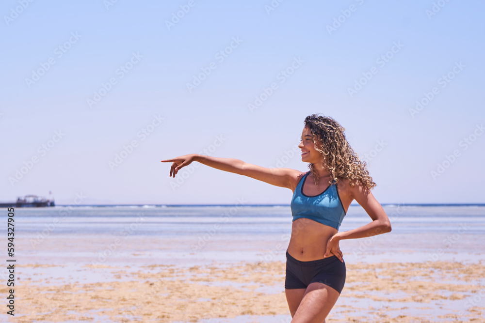 Portrait of young beautiful Brazilian girl staying on warm sunny beach and laughing.Latin woman with long curly hair enjoying her summer vacation on a sunny day. Portrait of young beautiful Brazilian girl staying on warm sunny beach and laughing.Latin woman with long curly hair enjoying her summer vacation on a sunny day.