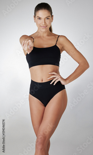 Im ready for summer, are you. Studio shot of an attractive young woman posing in her underwear and pointing at you against a grey background. © S Fanti/peopleimages.com