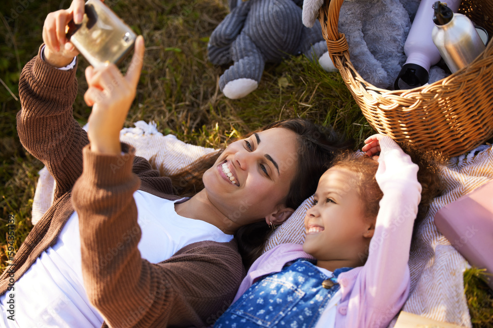 Obraz premium Selfie time. High angle shot of an attractive young woman and her daughter taking selfies during their picnic in the park.