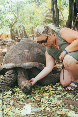 Woman poses with a giant turtle at the tortoise sanctuary on Prison Island, Zanzibar Tanzania