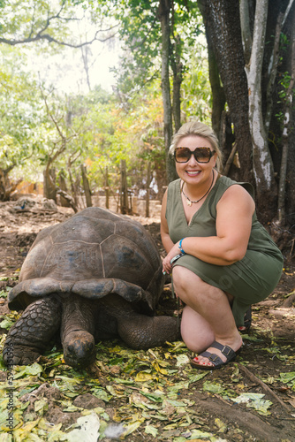 Woman poses with a giant turtle at the tortoise sanctuary on Prison Island, Zanzibar Tanzania