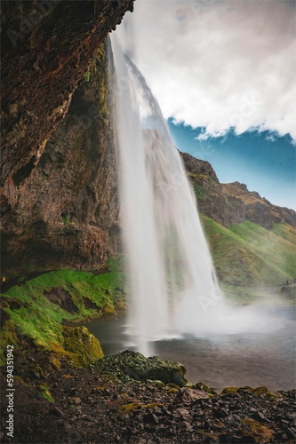 Majestic Seljalandsfoss waterfall cascades down behind a rocky outcrop in Iceland.