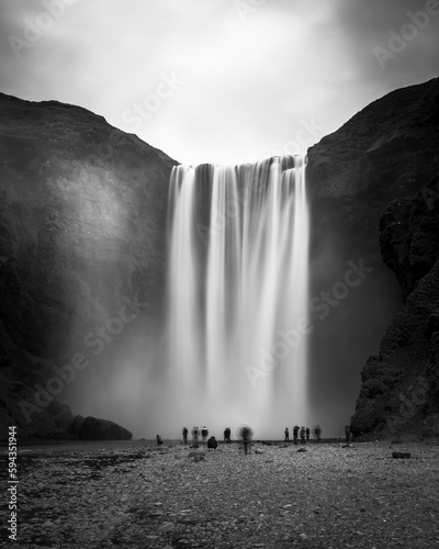 Majestic Skogafoss waterfall cascading down a hillside and hikers near the shoreline
