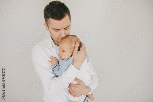 Father and baby boy, wearing casual clothes on white background.