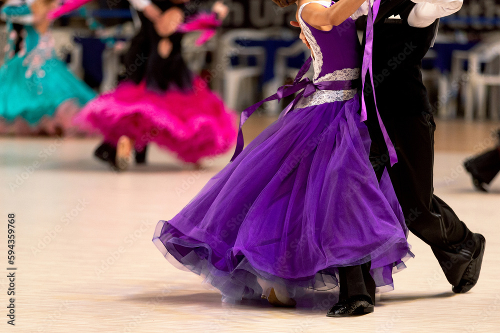 young couples dancers dancing waltz in dancesport competition, colorful dresses for girls and black tail suit for boys