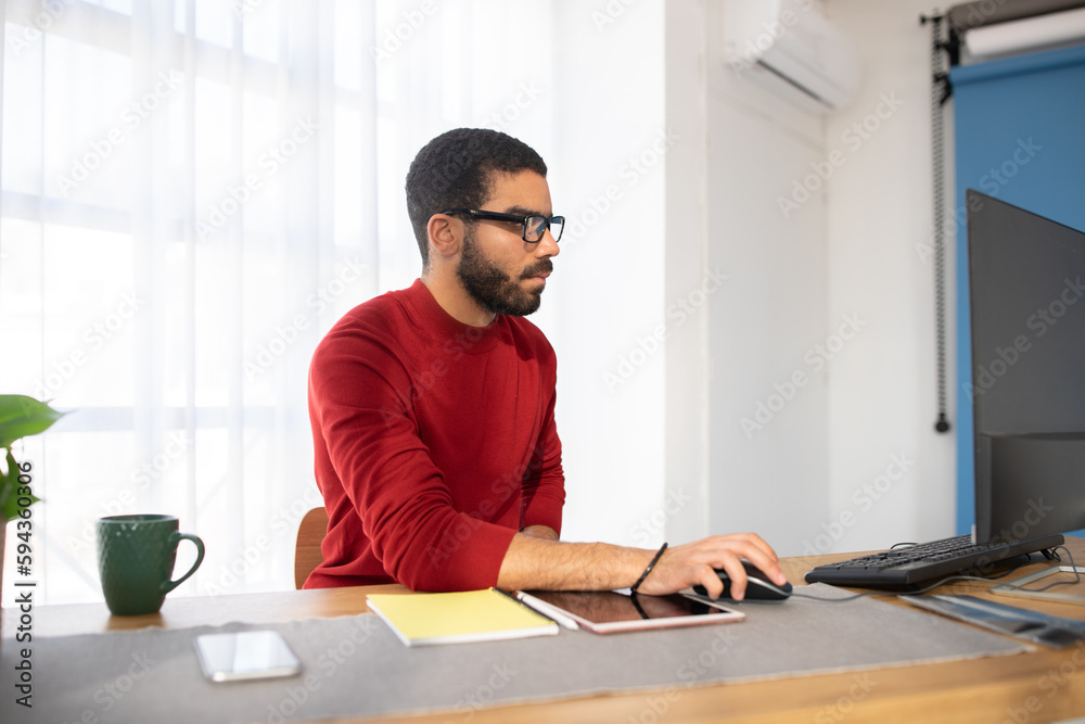 Concentrated young man graphic designer sitting at desk at office