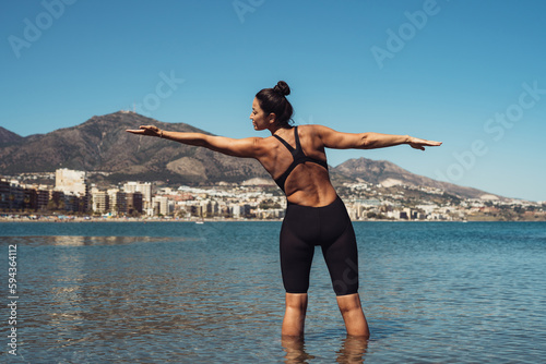 a girl swimmer in a black jumpsuit is swimming in the sea warming up doing exercises for swimming