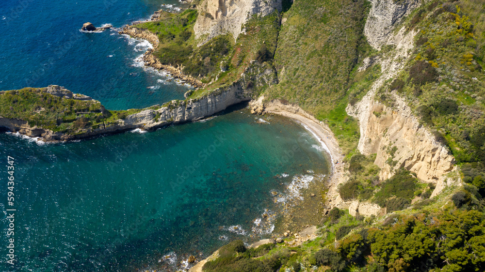 Aerial view on the Trentaremi bay of Posillipo, a district of Naples, Italy. There is a small empty beach in a cove. The coast overlooks the Mediterranean Sea.