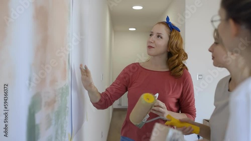 Female roommates using paint roller to decorate the walls in their new home.	
