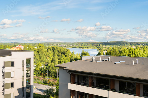 Building with apartments, condos in residential area. Park, green forest and lake landscape view. Outside facade of house. Rental housing or real estate. City in Finland in Summer. Scandinavian design