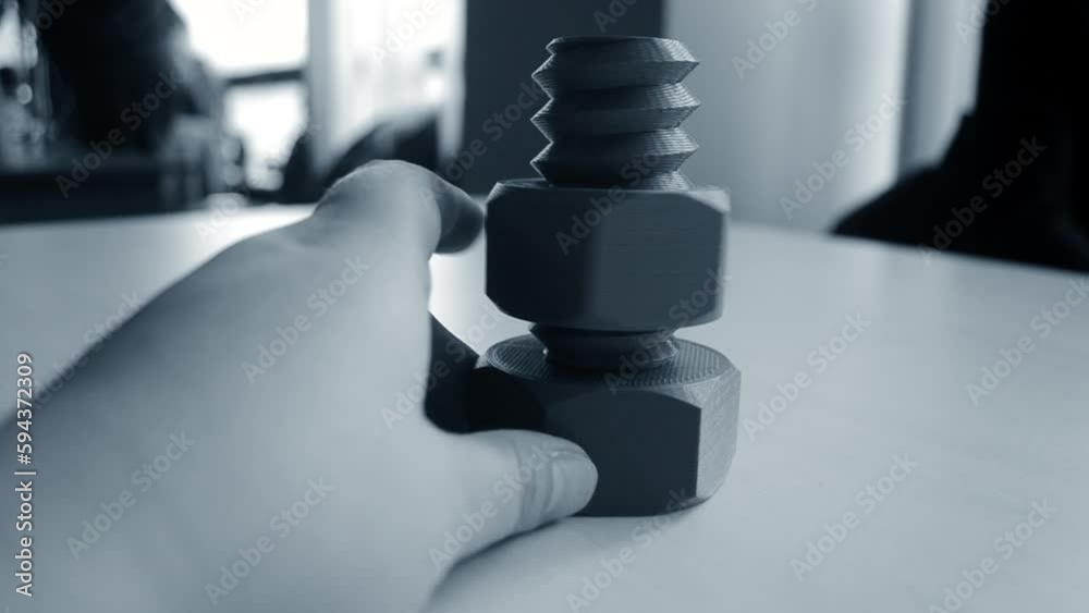 Person twisting with finger nut on plastic bolt printed on 3D printer. Models printed on 3D