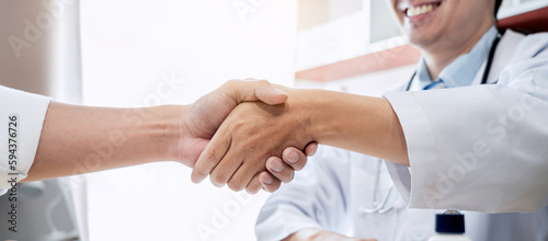 Male doctor in white coat shaking hands with the patient after s