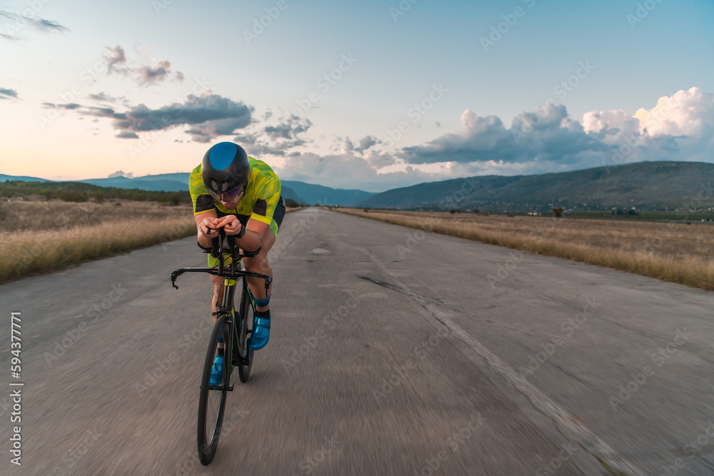 Triathlete riding his bicycle during sunset, preparing for a marathon. The warm colors of the sky provide a beautiful backdrop for his determined and focused effort. Triathlete riding his bicycle during sunset, preparing for a marathon. The warm colors of the sky provide a beautiful backdrop for his determined and focused effort.