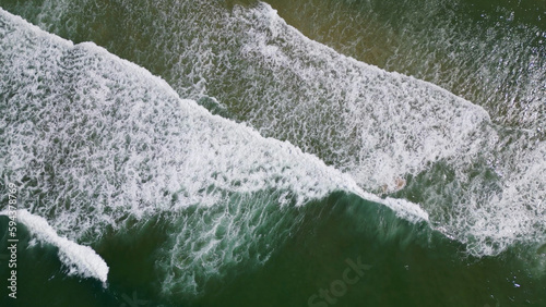 Overhead view of waves crashing on sandy beach