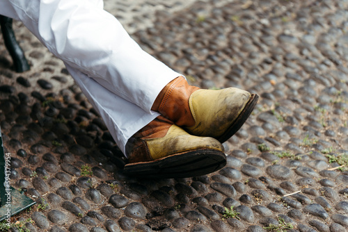 Fotografie Men's feet in traditional leather boots carrier on toboggan baskets (Carreiros do Monte) in Portugal island of Madeira