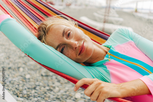 Happy smiling carefree young woman relaxing in a hammock on the beach. photo