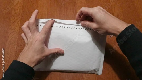 家で届いた封筒を開ける手元の映像