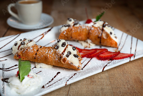 Italian cannoli on a white plate with strawberries and chocolate chips