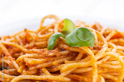 pasta on a white plate with basil leaves on a white background. pasta on a plate